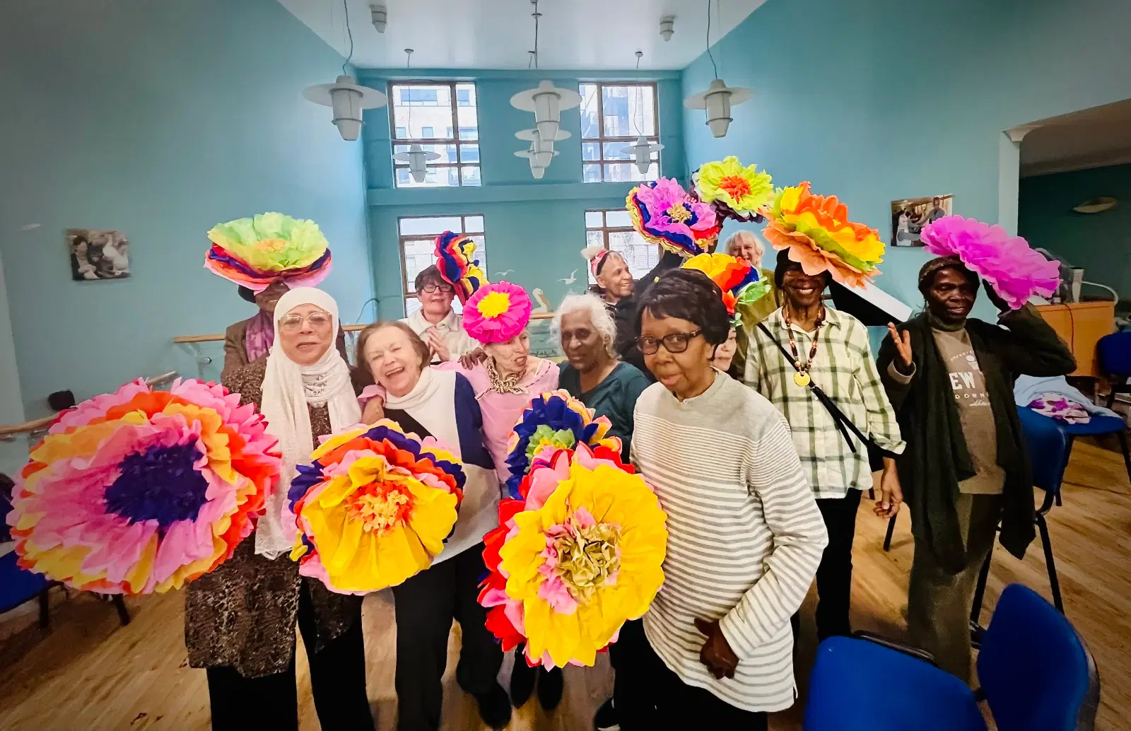 A diverse group of individuals joyfully holding vibrant paper flowers.