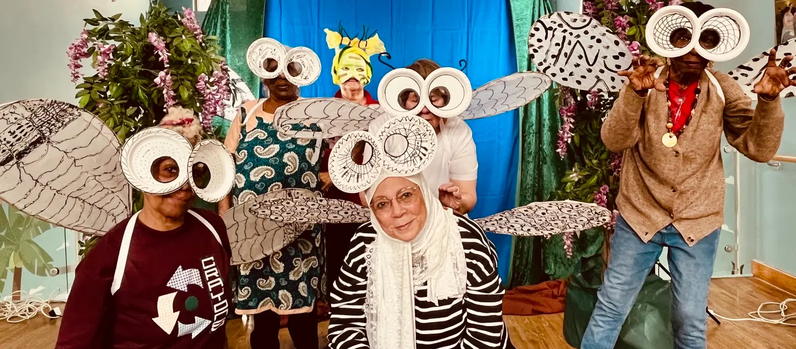 A group of people playfully posing with owl masks and whimsical headgear at a fun-themed event or party.