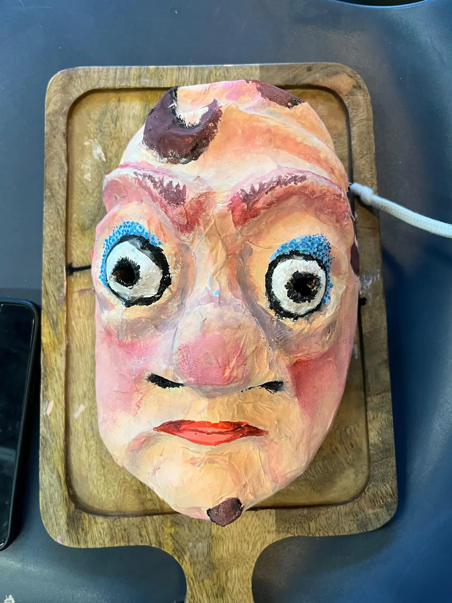 Mask with large eyes and nose on a chopping board