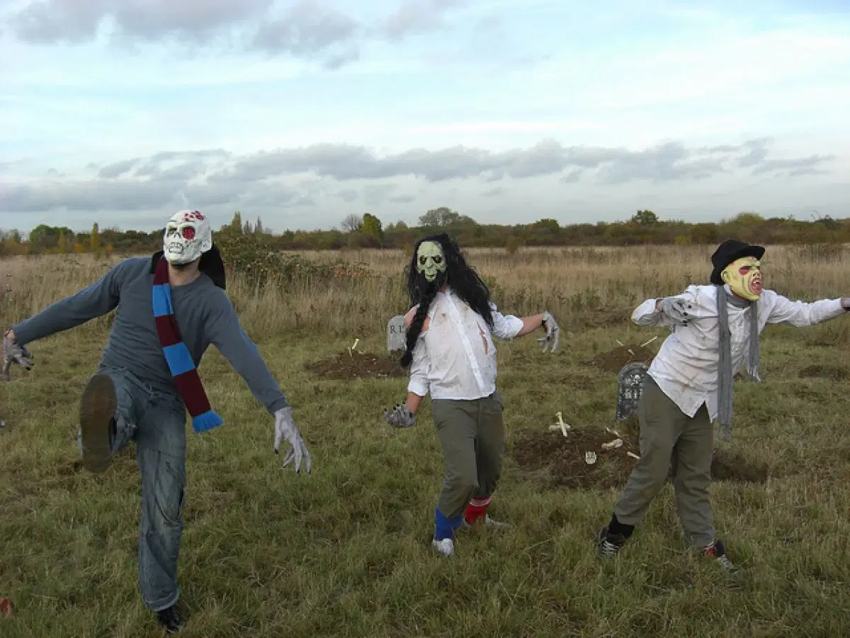 Three actors dressed in ripped clothing and scary mask in a field